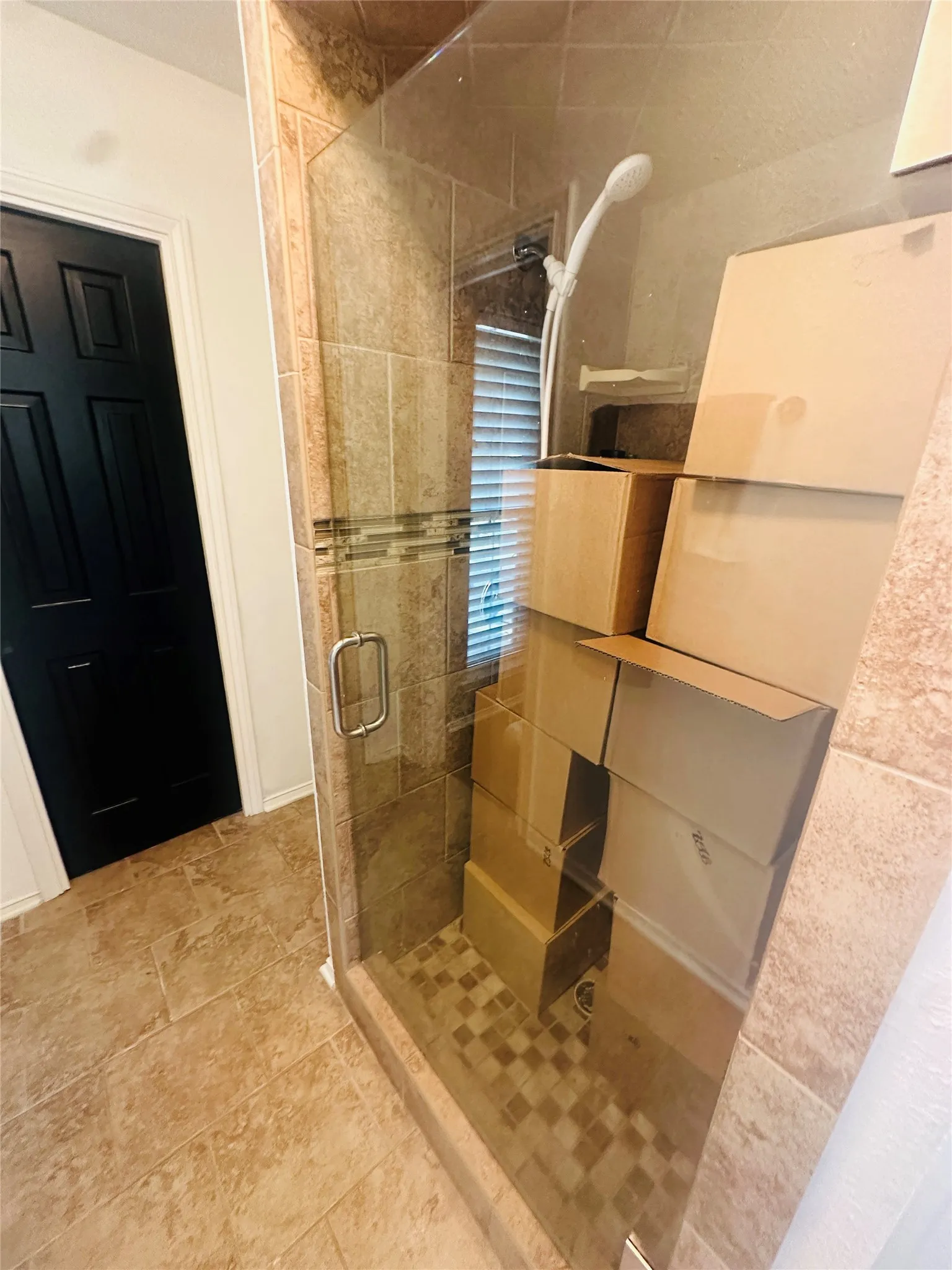 Glass-enclosed shower with a tiled surround, decorative mosaic accent band, and a mosaic tile shower pan