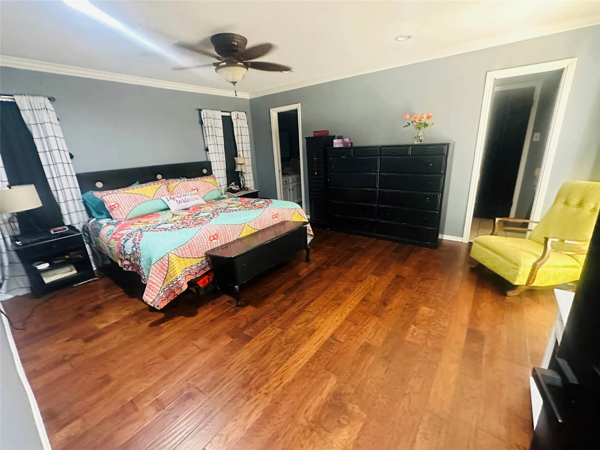 Wood-finish flooring, crown molding, and a ceiling fan