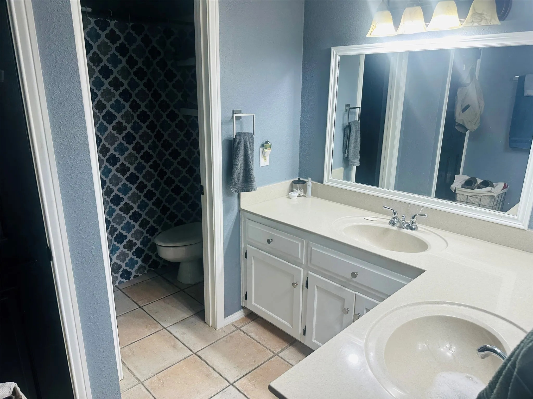 Double vanity with integrated sinks, white cabinetry, and a large framed mirror
