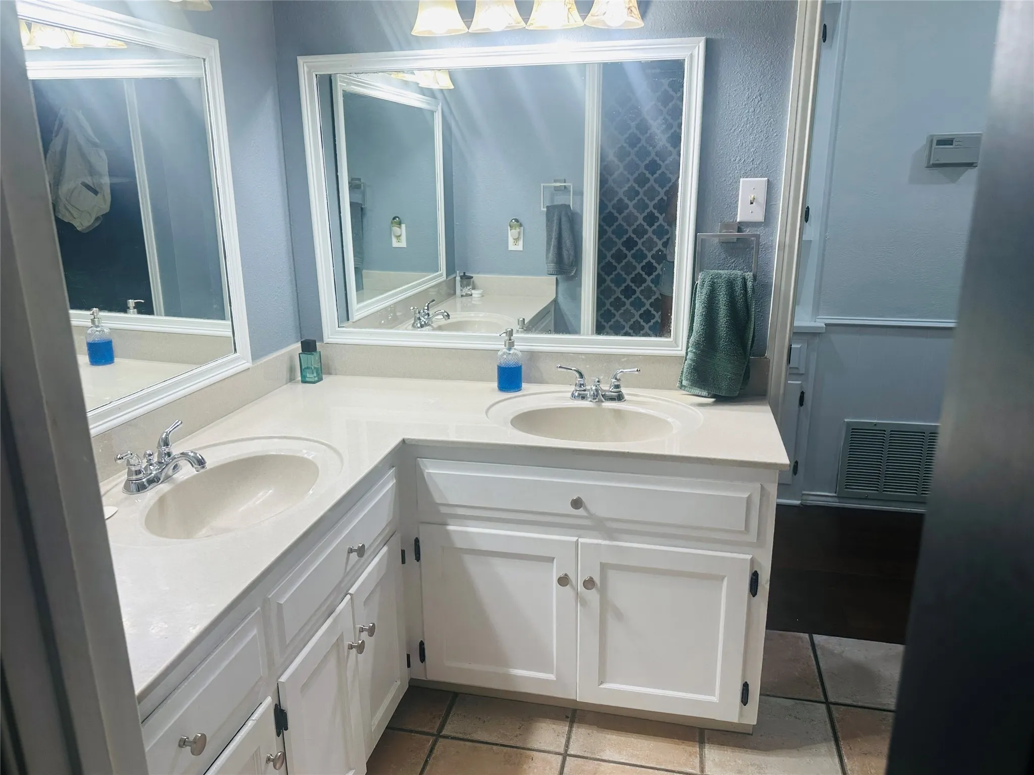 Dual vanity with integrated sinks, white cabinetry, chrome fixtures, and framed mirrors
