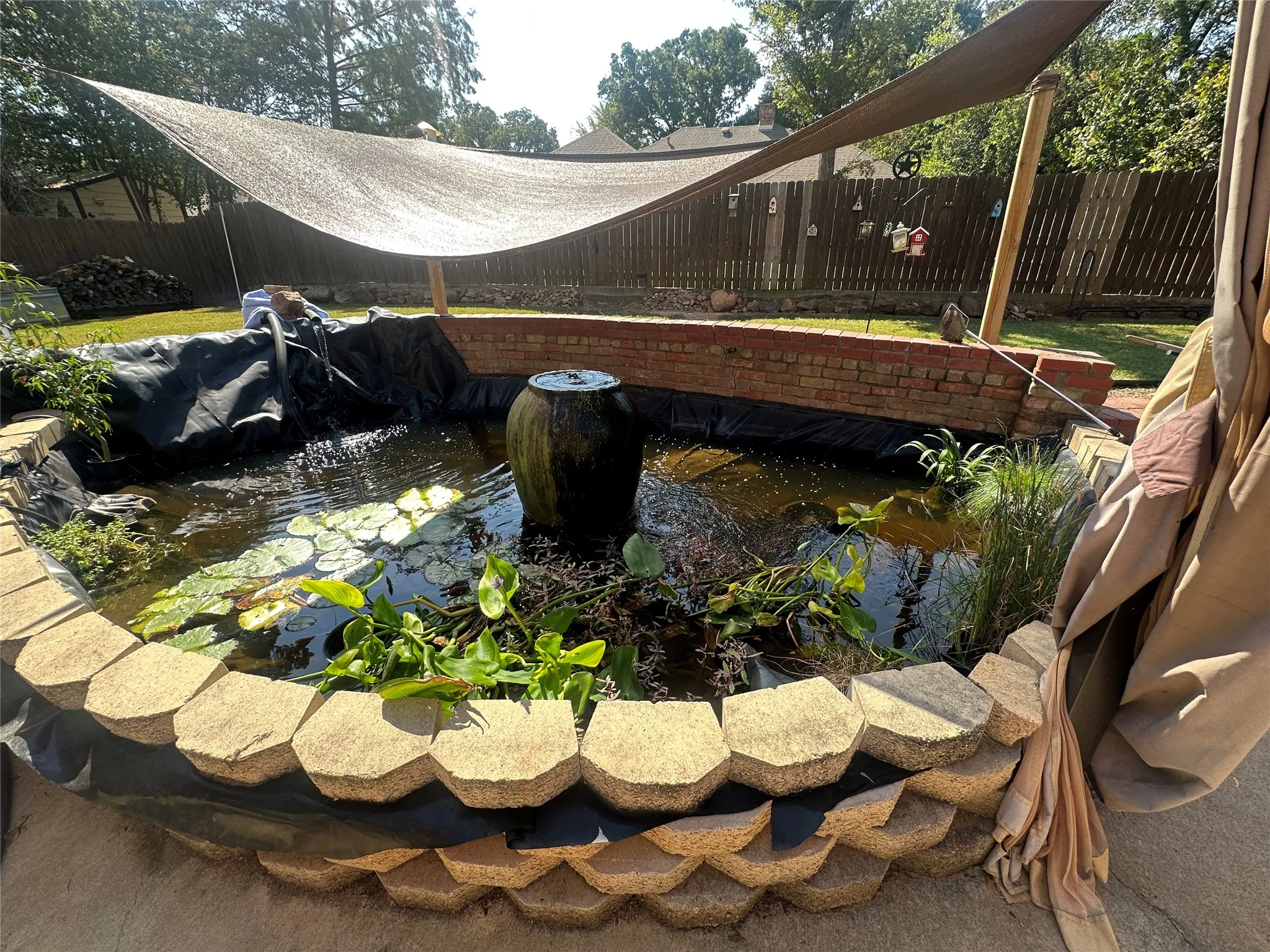 Water feature with a stone block border, integrated water fountain, and aquatic plants