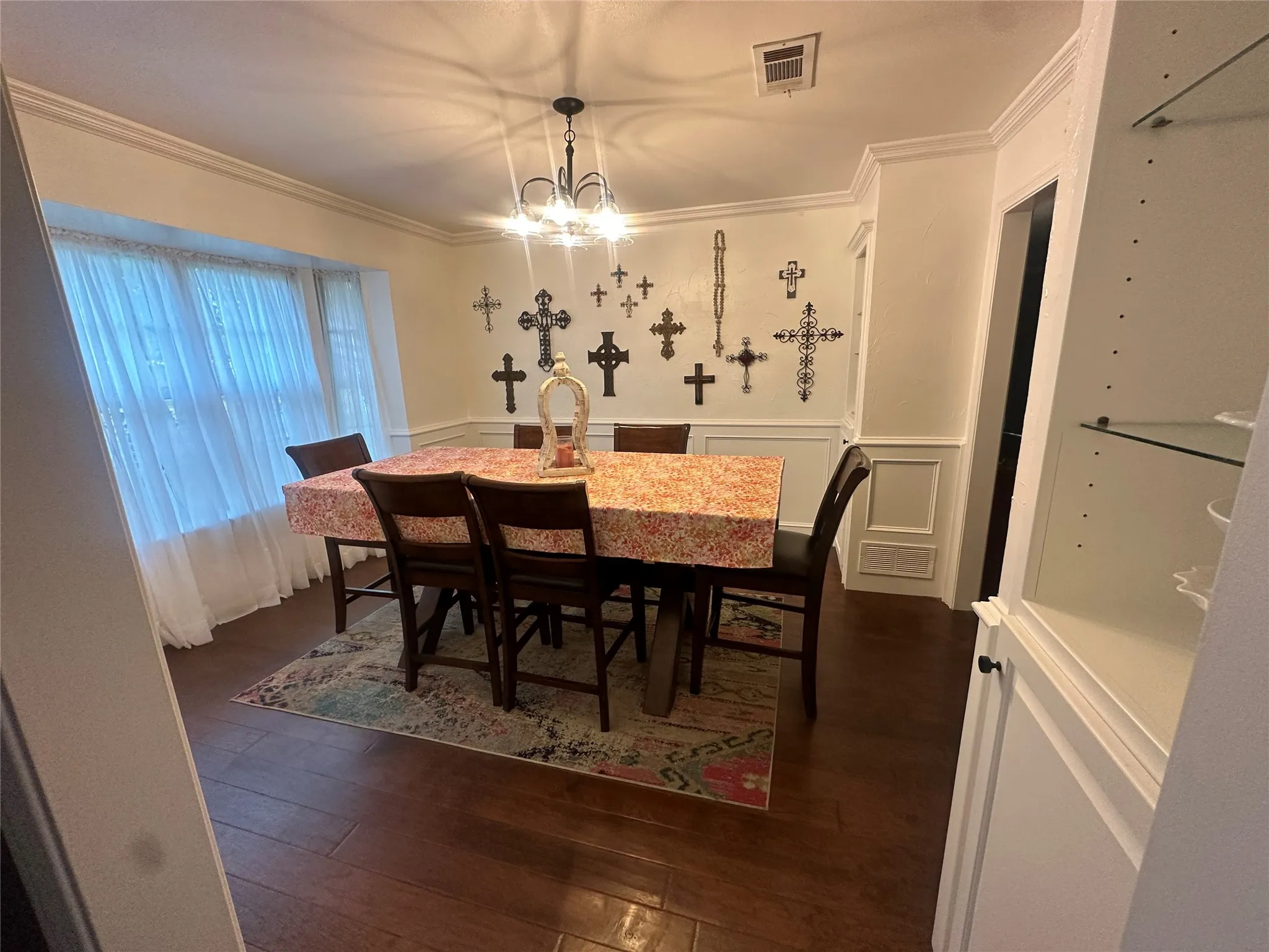 Wood-finish flooring, crown molding, chair rail molding, bay window, built-in cabinetry with glass shelving