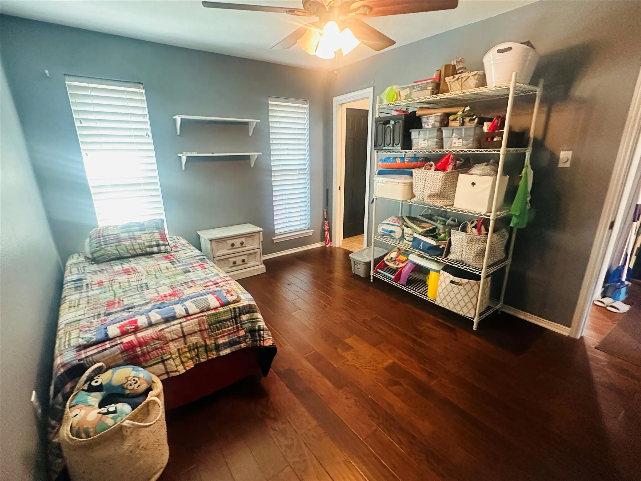 Wood-finish flooring, two window treatments, and a ceiling fan with lighting