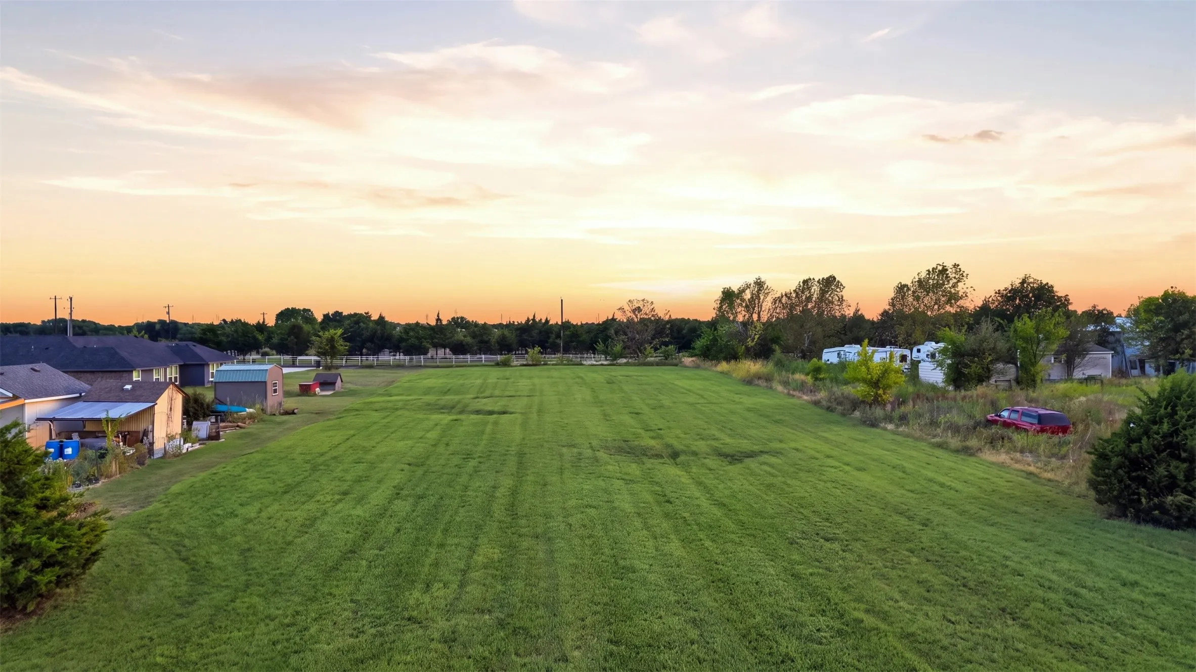 Expansive grassy lot with surrounding mature trees