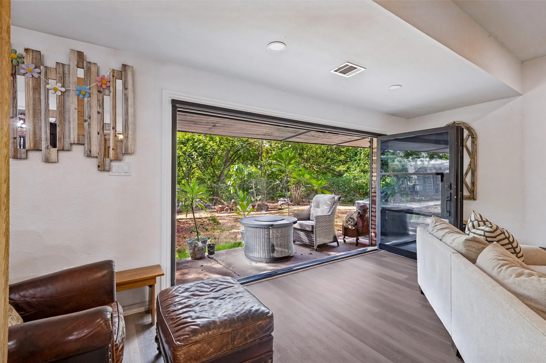 Spacious great room with abundant seating space, ceiling fan and a dramatic wall of glass doors opening to the covered patio and tree-filled backyard.