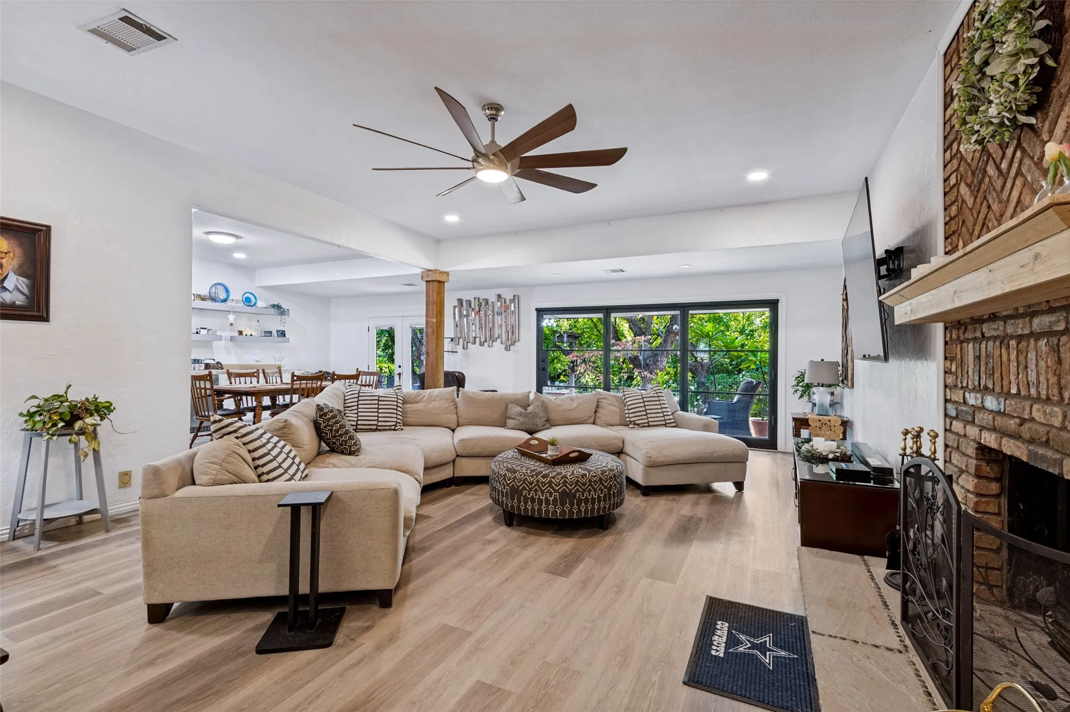 Expansive great room featuring a brick fireplace, recessed lighting and ceiling fan, with an open flow to the adjoining breakfast area.