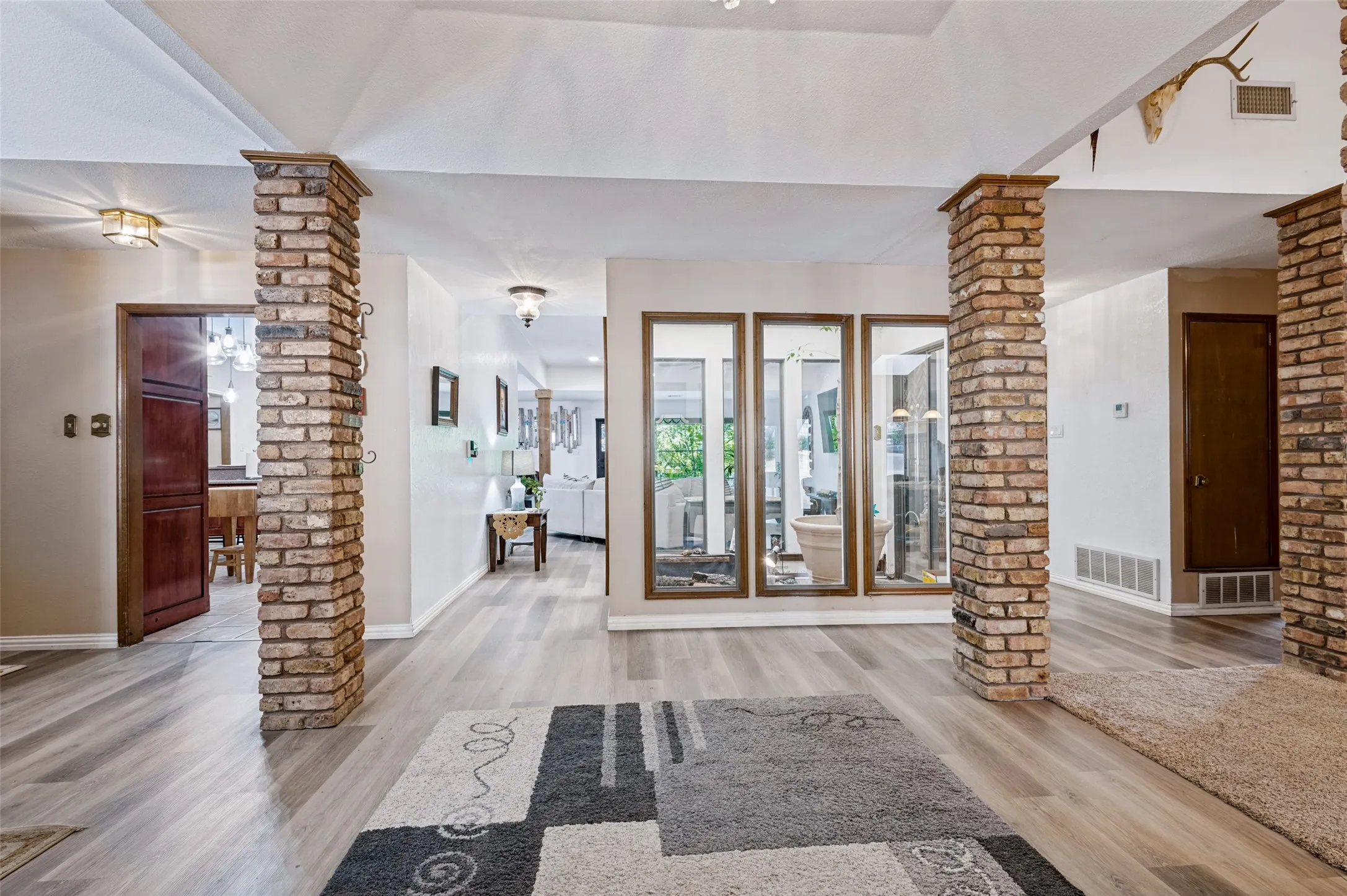 Welcoming entry framed by distinctive brick columns, with an interior atrium bringing natural light and greenery into the heart of the home.