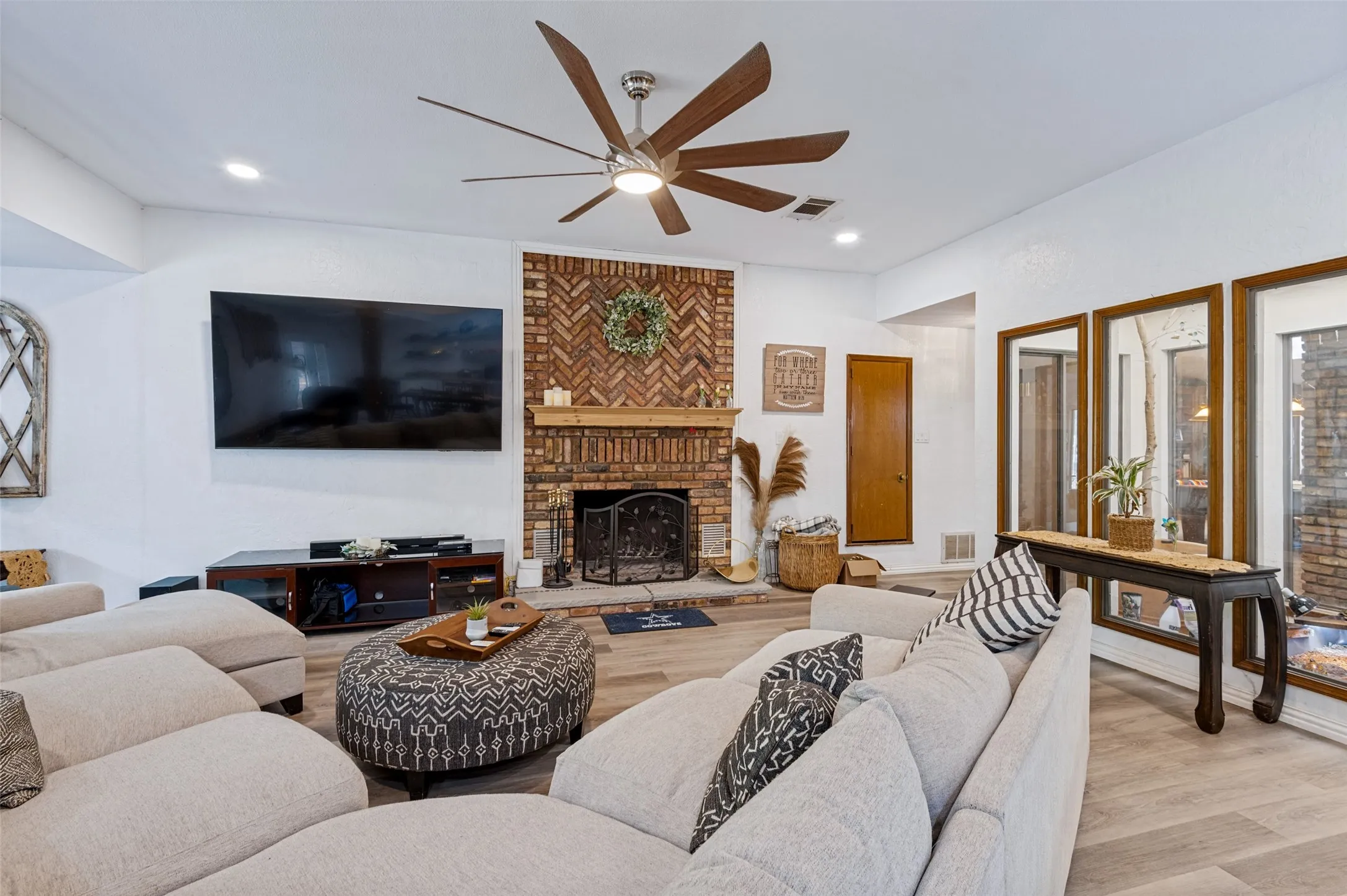 Distinctive herringbone brick fireplace with wood mantel creates a striking architectural focal point in the great room.