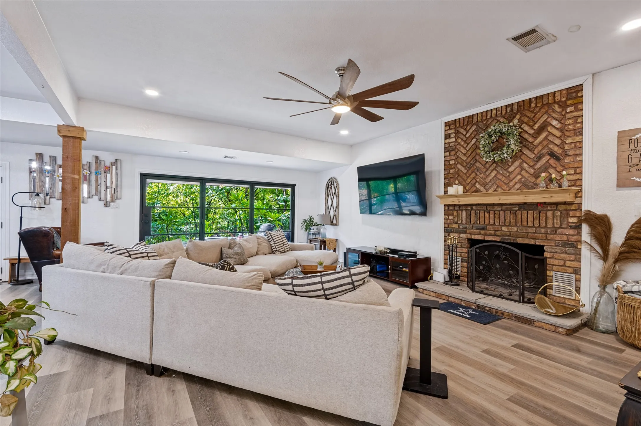 Great room featuring a striking herringbone brick fireplace with wood mantel and hearth, recessed lighting and ceiling fan.