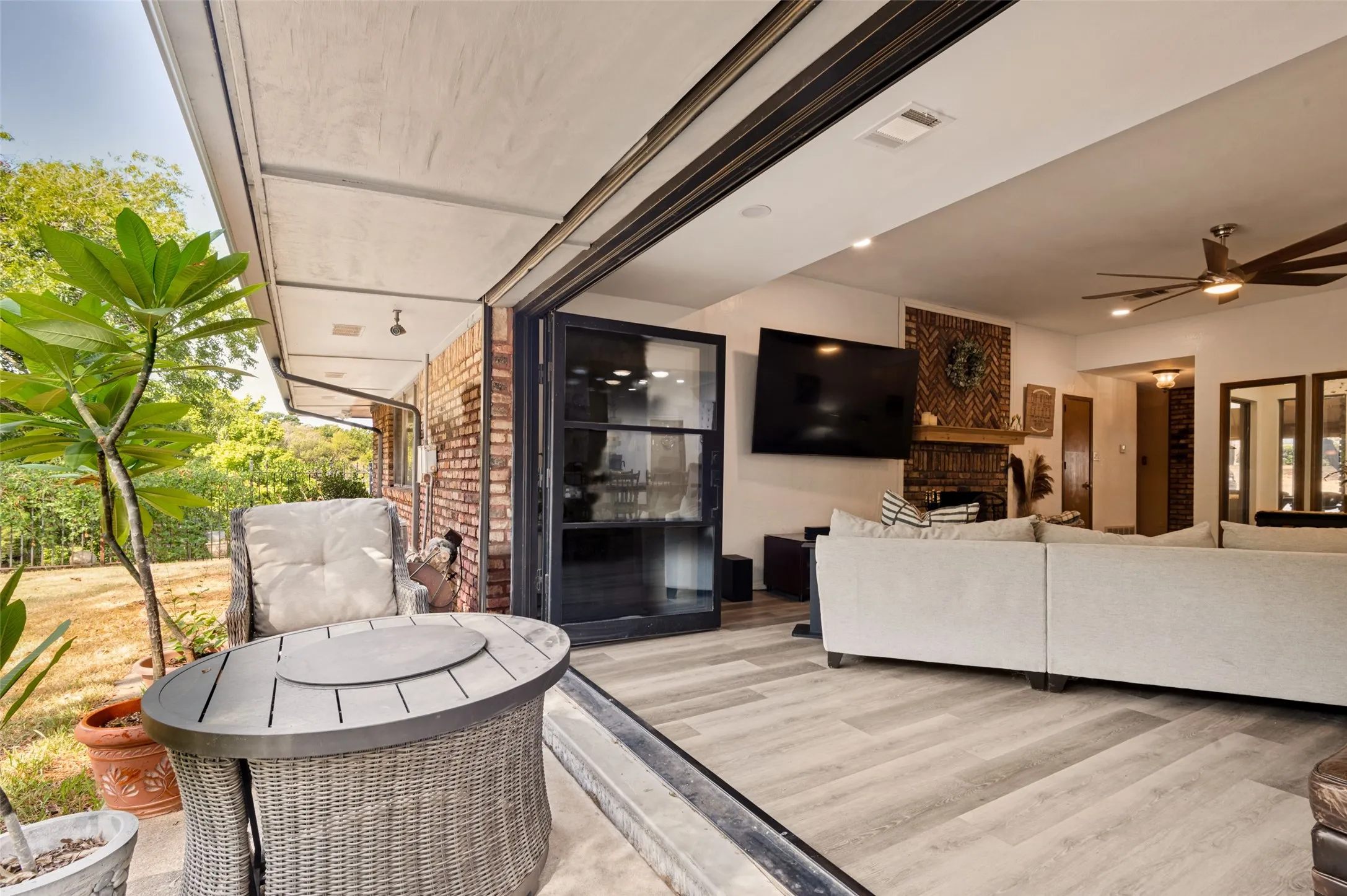 Great room with a dramatic wall of glass doors opening directly to the covered patio and tree-filled backyard, creating a seamless indoor-outdoor living experience.