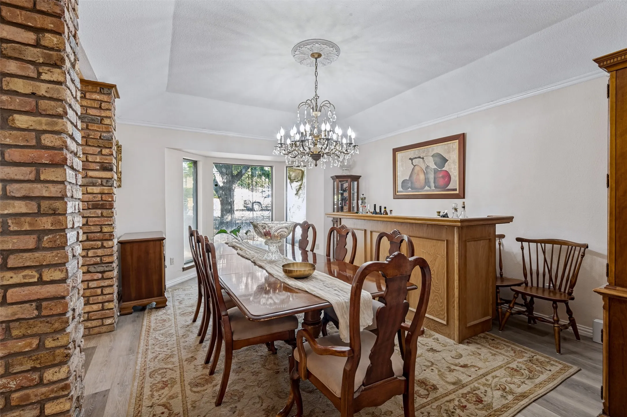 Formal dining room framed by distinctive brick columns and featuring an elegant chandelier, generous entertaining space and natural light.