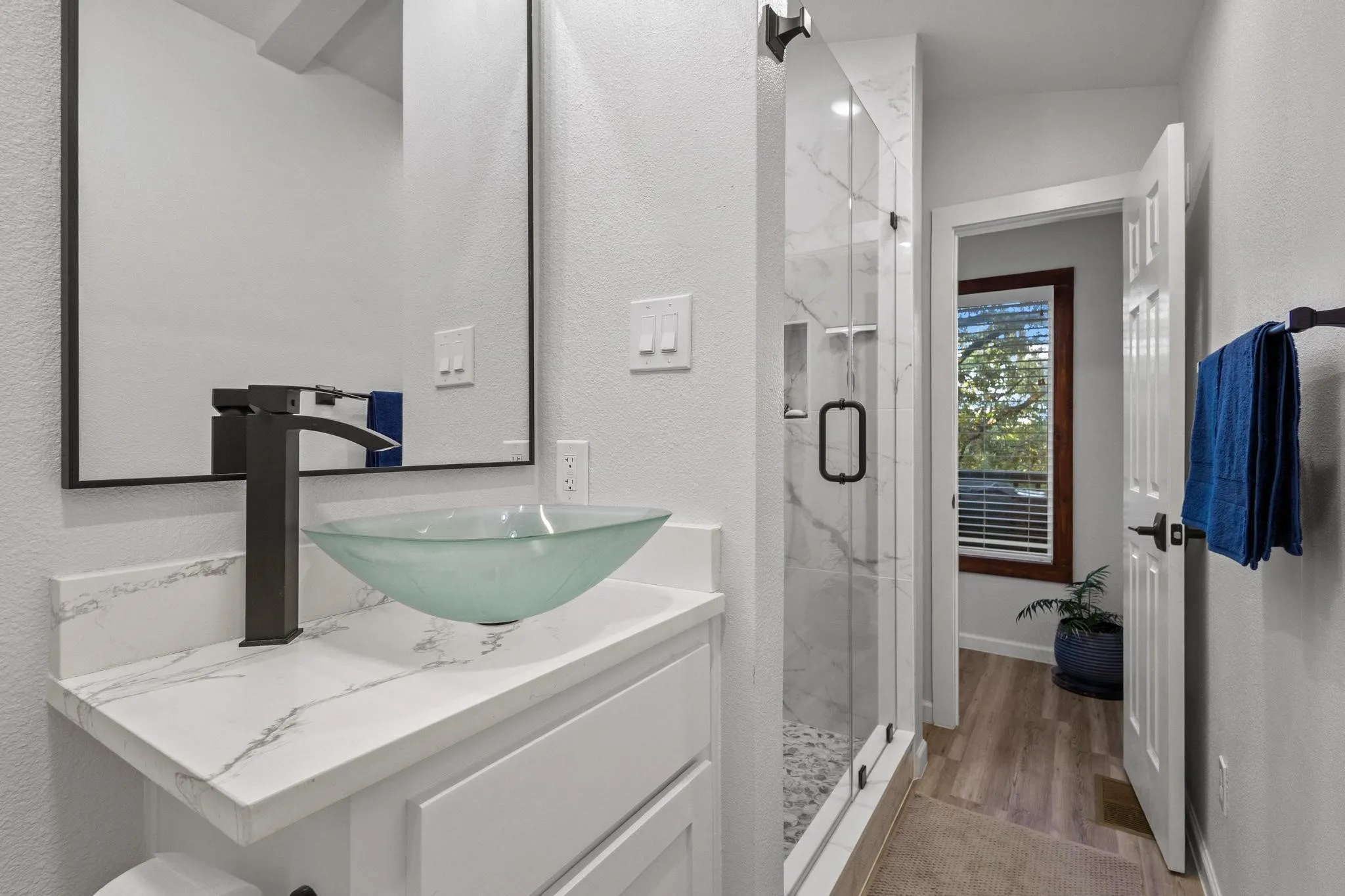 Quartz Vanity Top, Frosted Glass Top-Mount Sink, Matte Black Fixtures and Custom Tiled Shower with Glass Doors