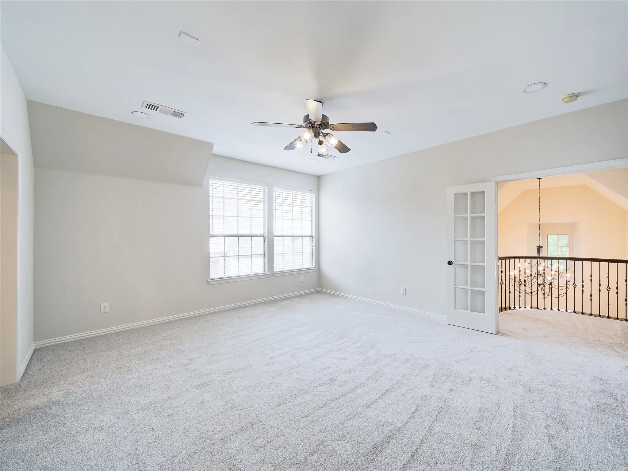 Recessed lighting, ceiling fan, two windows with blinds, gray carpeting, and French doors