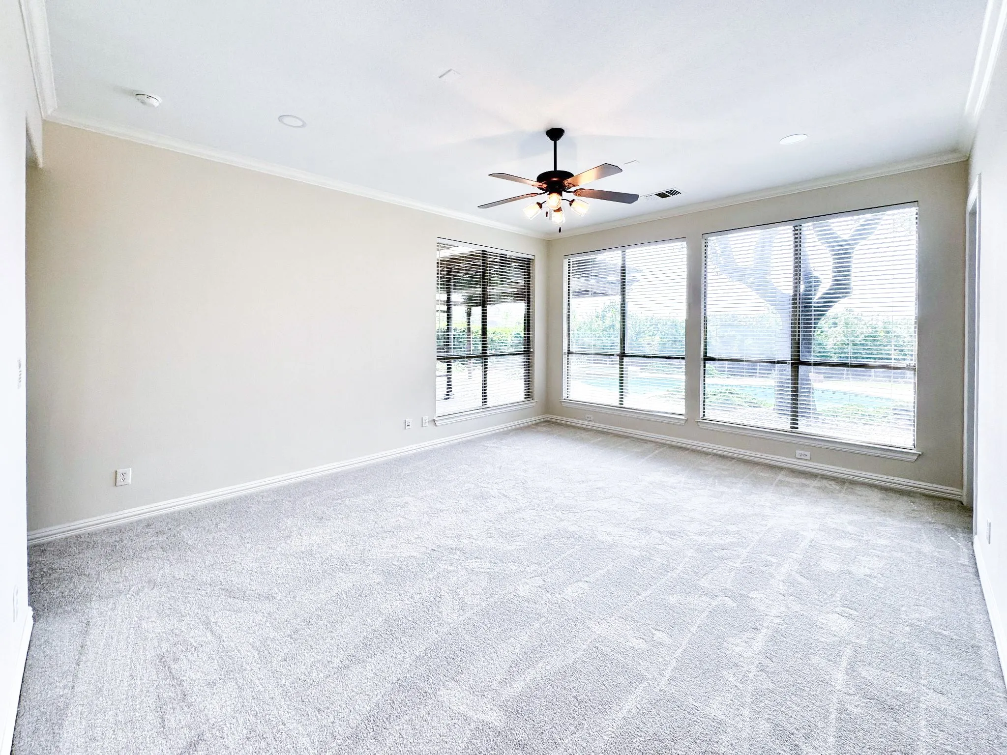 Light-filled interior space with multiple large windows, a ceiling fan, recessed lighting, and crown molding