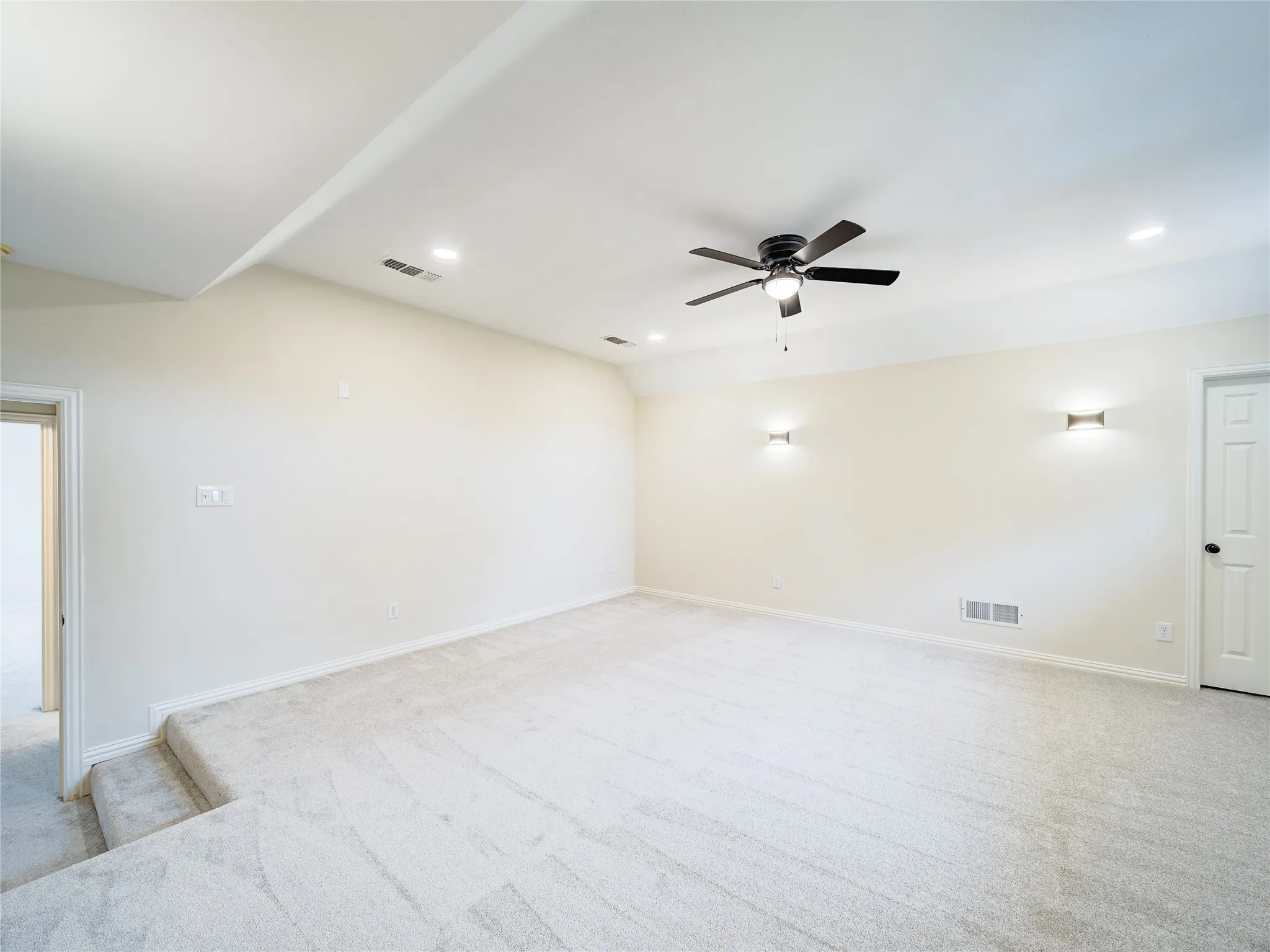 Spacious carpeted room with a ceiling fan, recessed lighting, and wall sconces