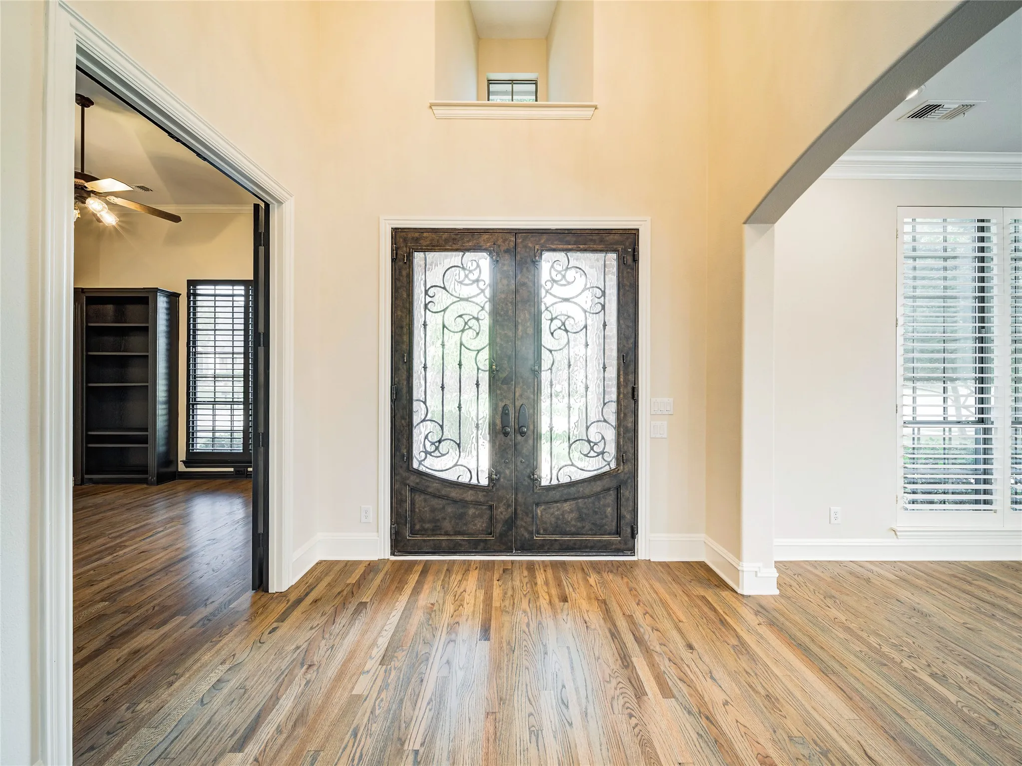 Hardwood flooring throughout the entry, double front doors with ornate ironwork, and tall ceilings
