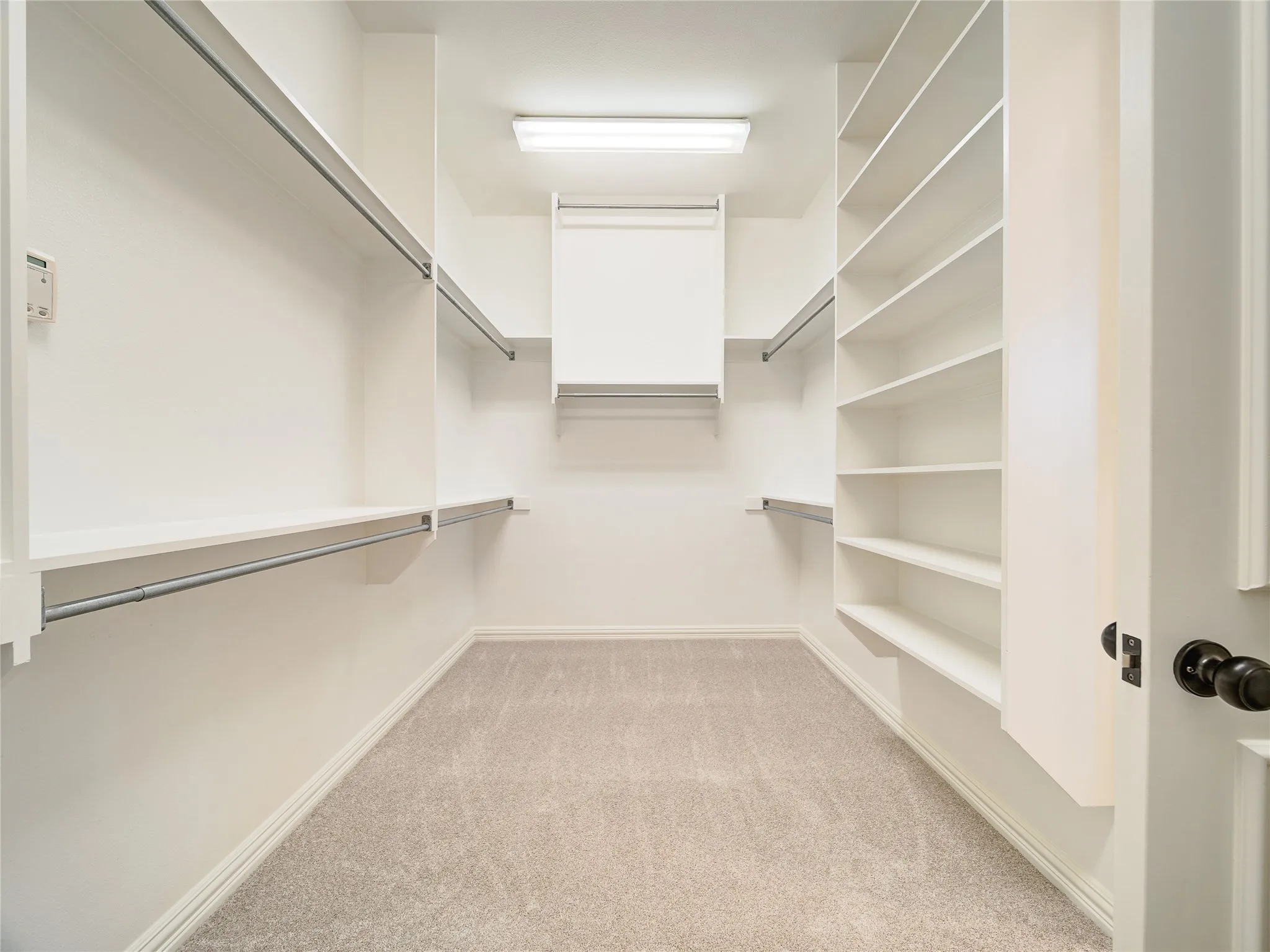 Walk-in closet with carpet flooring, extensive shelving, multiple hanging rods, built-in overhead storage, and recessed lighting