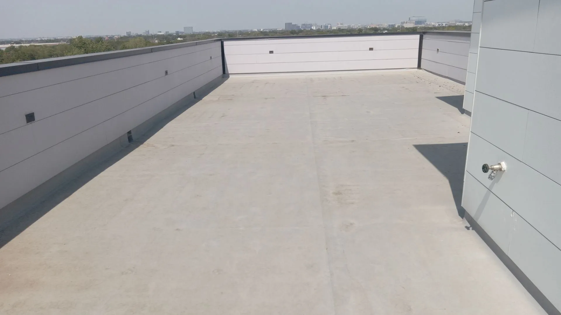 Expansive rooftop terrace featuring a concrete surface and perimeter walls