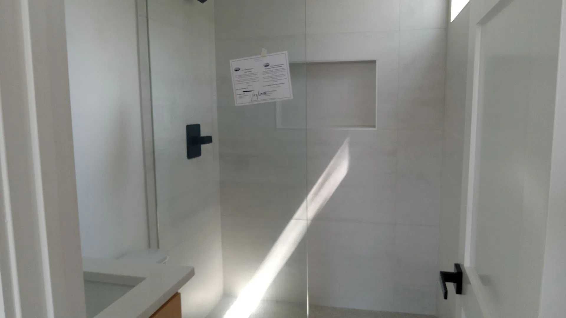Glass shower enclosure with matte black hardware and a tiled shower niche