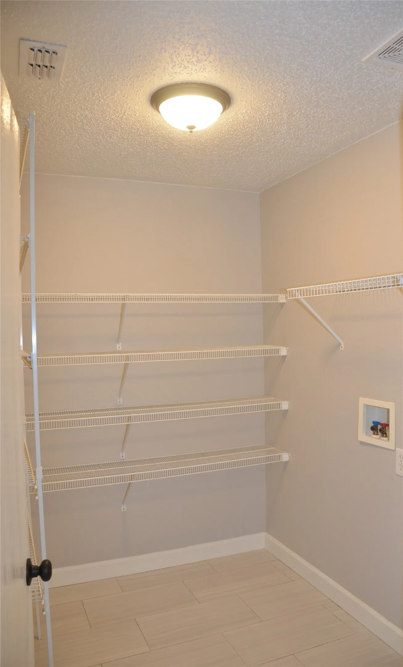 Pantry and laundry room featuring light-toned tile flooring, four tiers of wire shelving, and a flush mount ceiling light