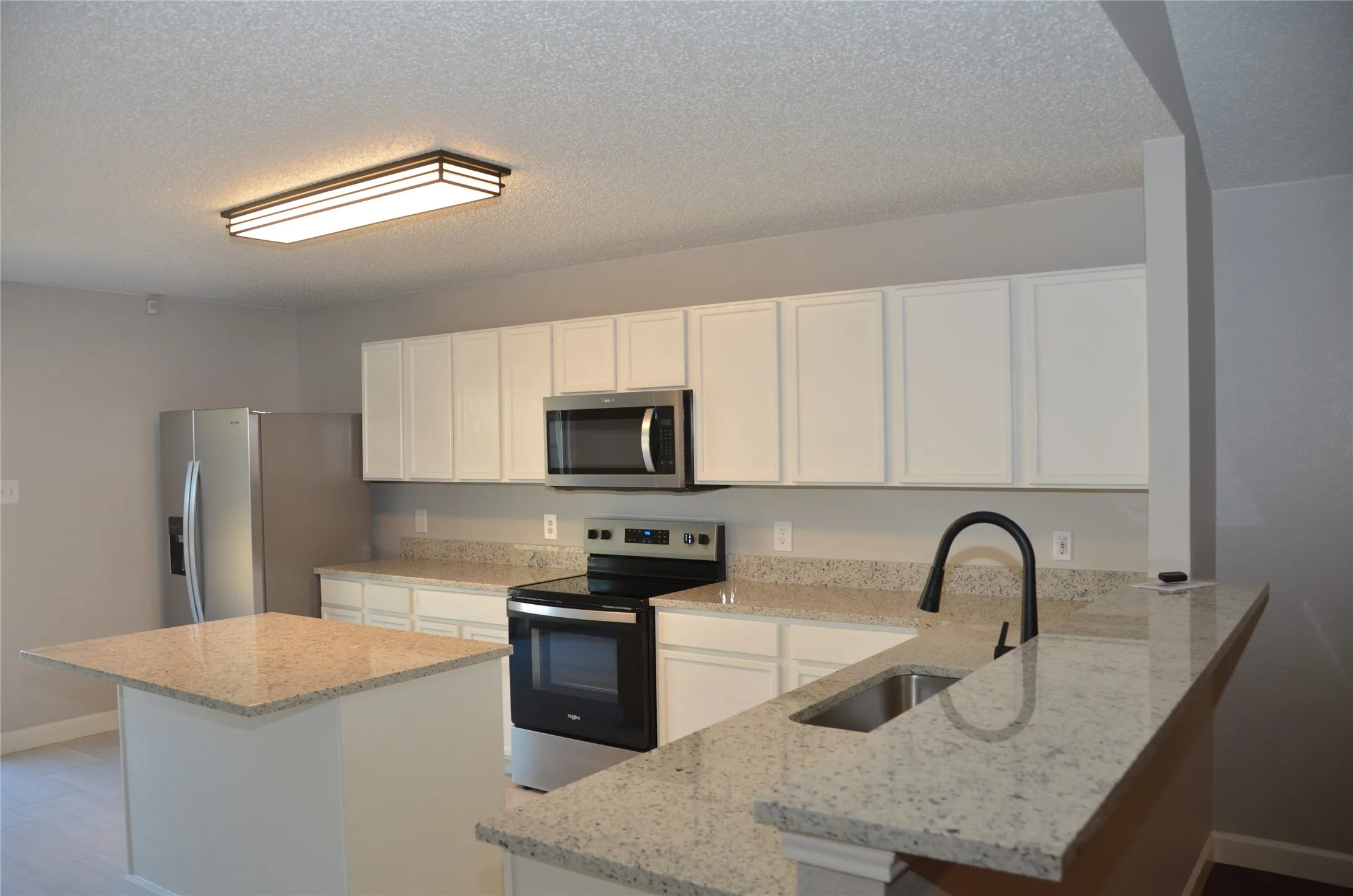 Kitchen featuring white shaker-style cabinetry, light-toned countertops, and stainless steel appliances