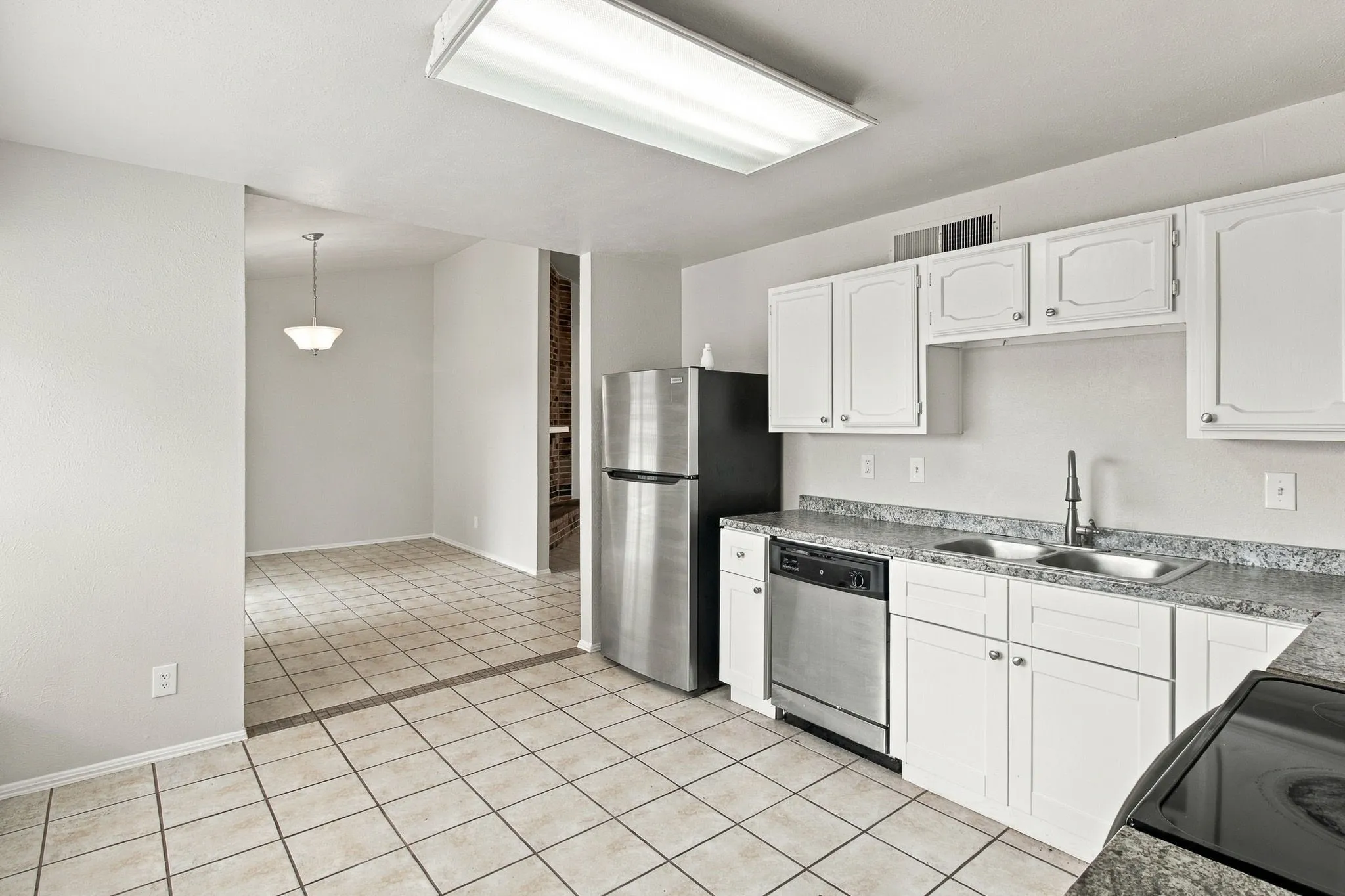 Kitchen featuring white cabinetry, a double basin stainless steel sink, a stainless steel dishwasher, and tile flooring