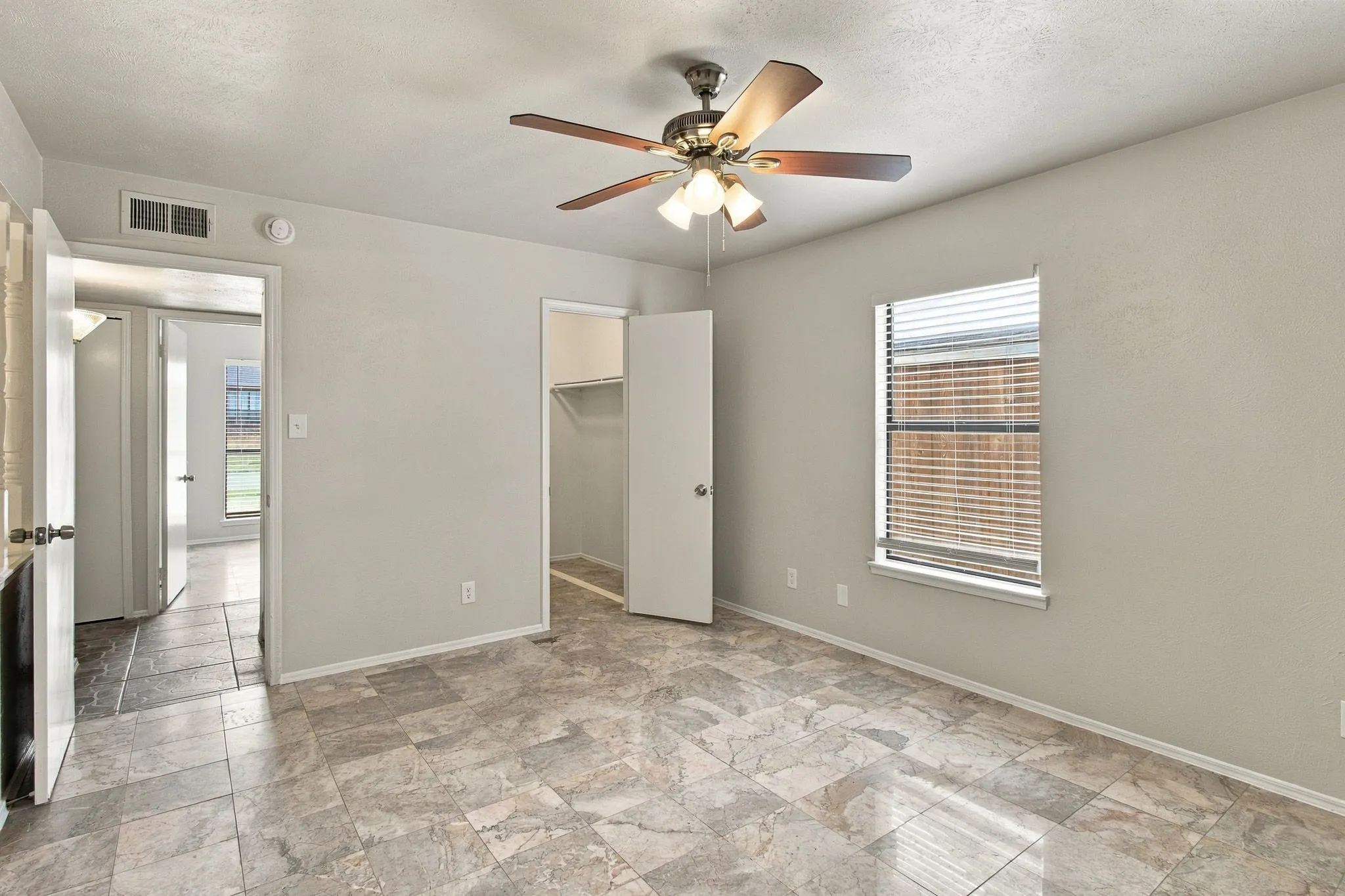 Neutral-toned tiled flooring, ceiling fan with integrated lighting, window with blinds, and white interior doors