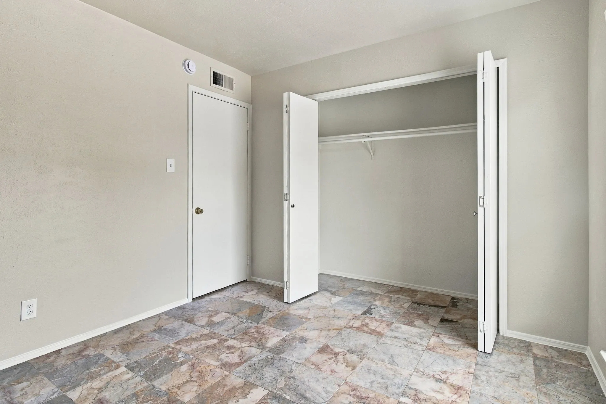 Tile-look flooring, white interior doors, and a built-in closet with shelving and hanging rod