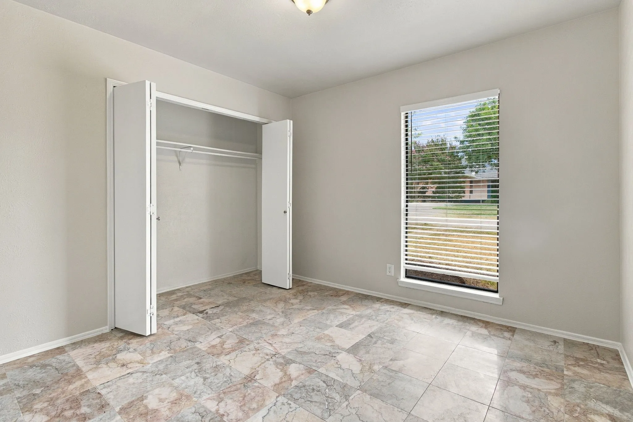 Light-colored walls, patterned tile flooring, and a window with blinds