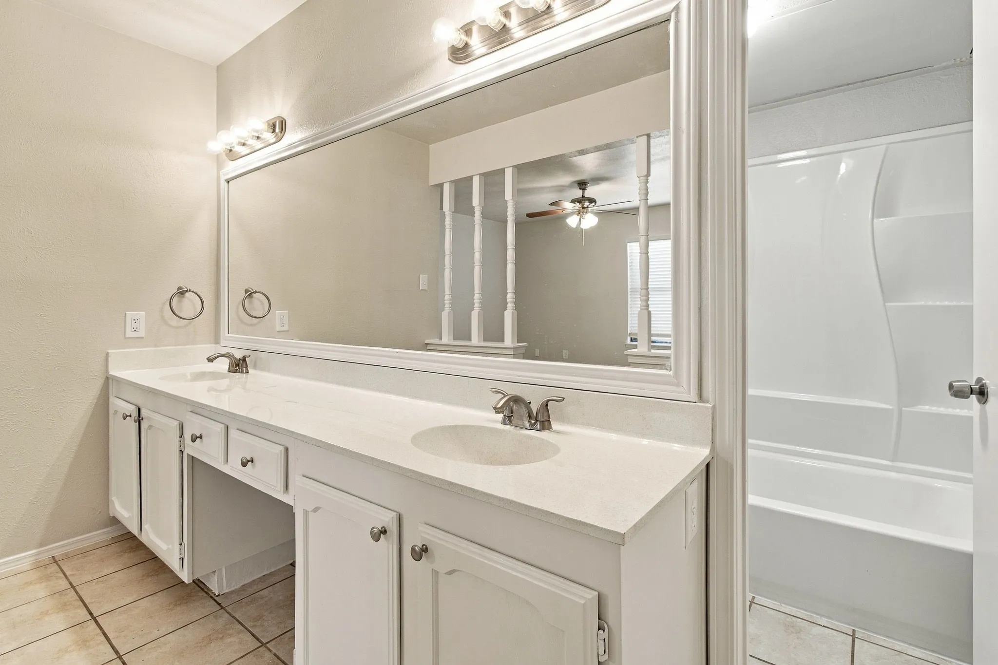 Dual vanity with undermount sinks, white cabinetry, and a large framed mirror