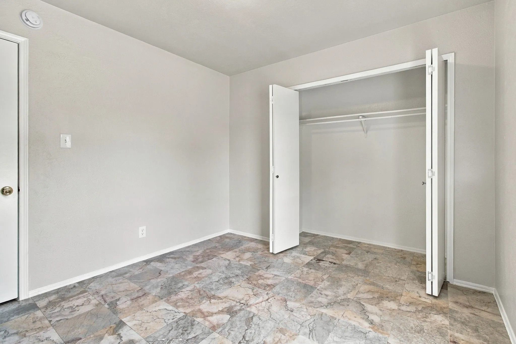 Neutral wall tones, patterned tile flooring, and a bi-fold closet with an integrated hanging rod