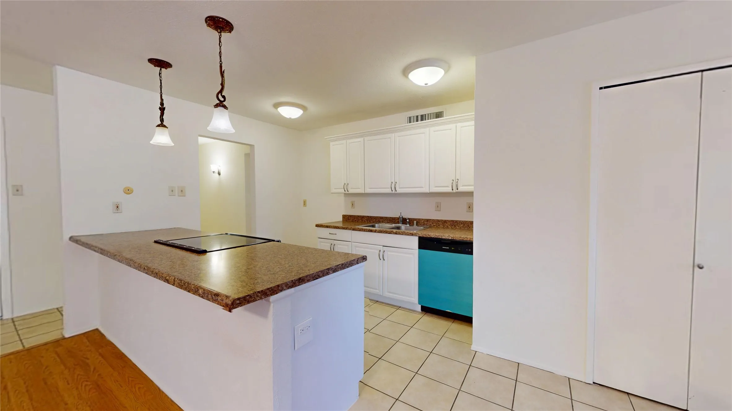 Kitchen featuring white cabinetry, light-toned countertops, a built-in cooktop, a turquoise dishwasher, and tile flooring