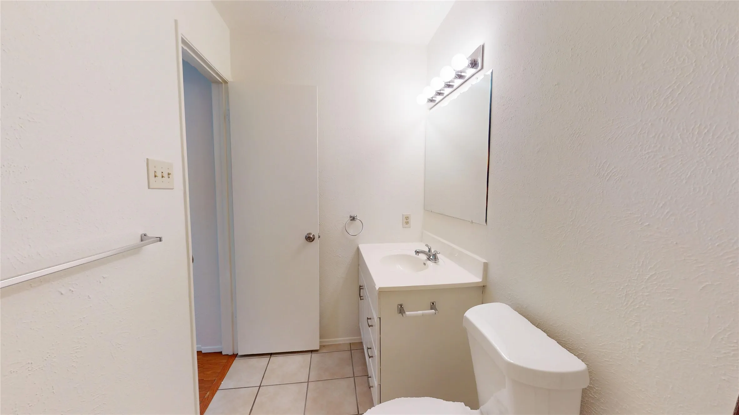 Vanity with integrated sink, wall-mounted mirror, and overhead vanity lighting