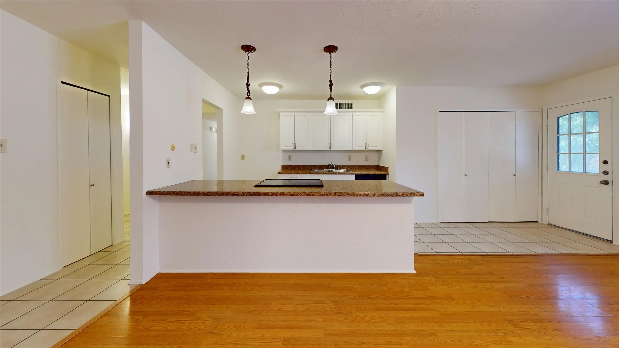 Kitchen with white cabinetry, built-in cooktop, and stone-finish countertops