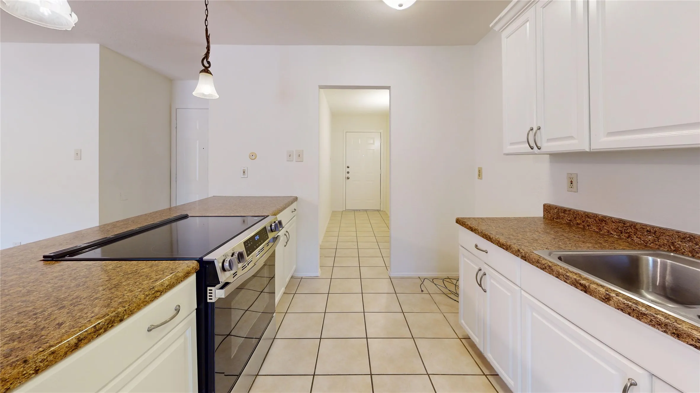 Well-appointed kitchen featuring white cabinetry, a stainless steel sink, a built-in range, a built-in oven, and tiled flooring