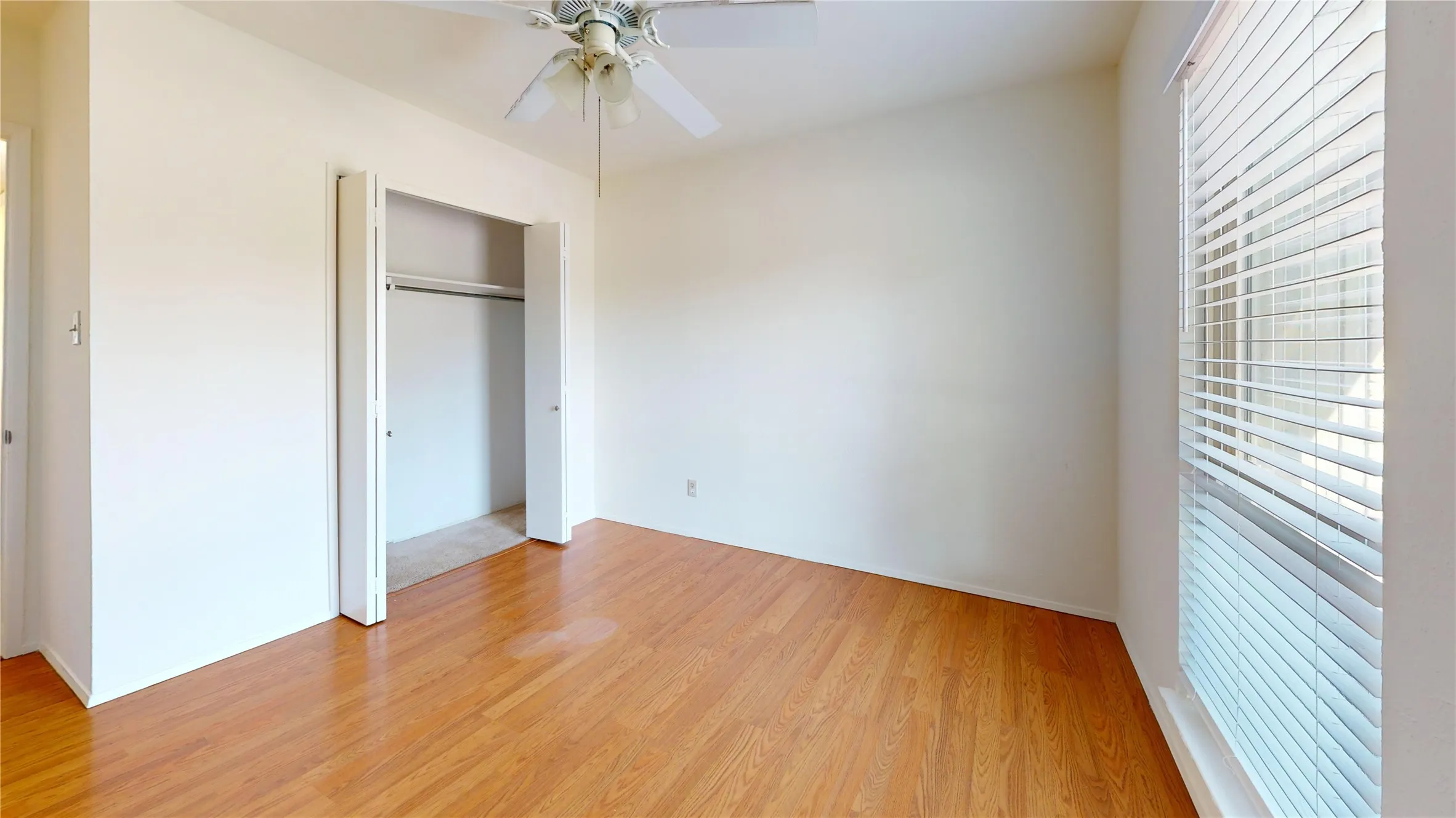 Wood-finish flooring, ceiling fan, and window with blinds