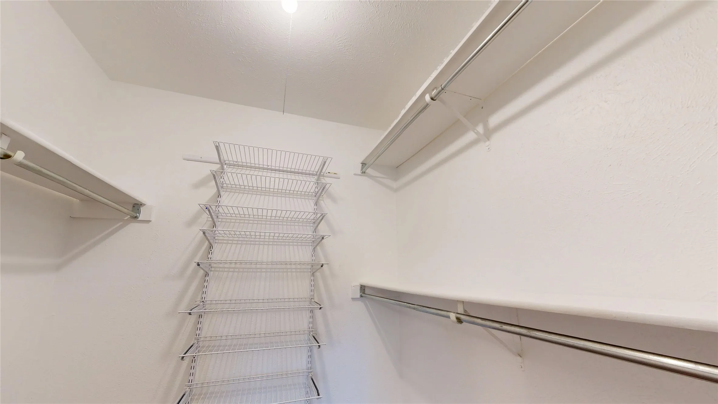 Built-in wire shelving, multiple hanging rods, and an overhead light fixture