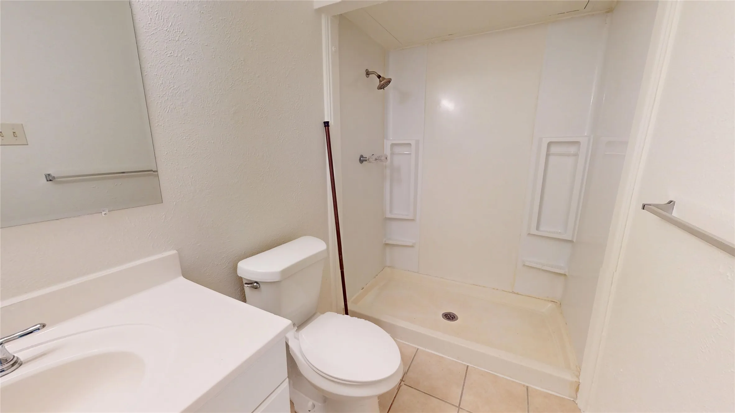Vanity with integrated sink, chrome faucet, wall-mounted mirror, and tile flooring