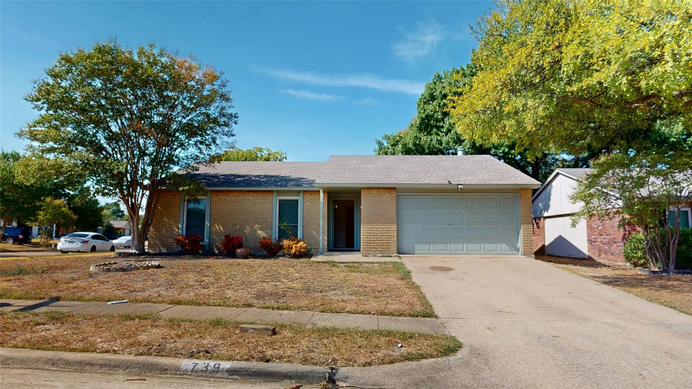 Brick veneer exterior with a light-colored garage door and a paved driveway