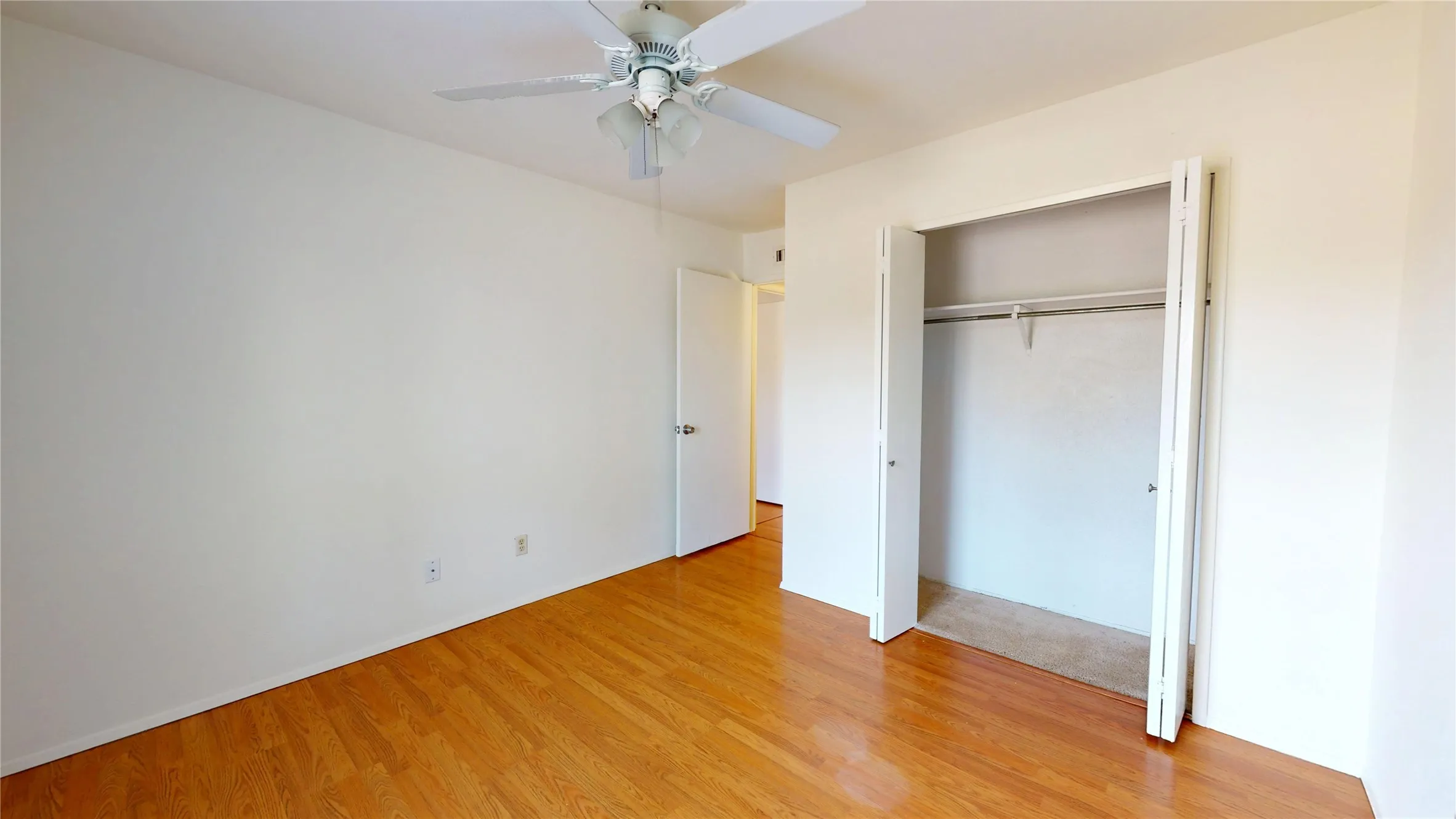 Wood-finish flooring, ceiling fan, bi-fold closet doors, built-in closet shelving, and a neutral color palette