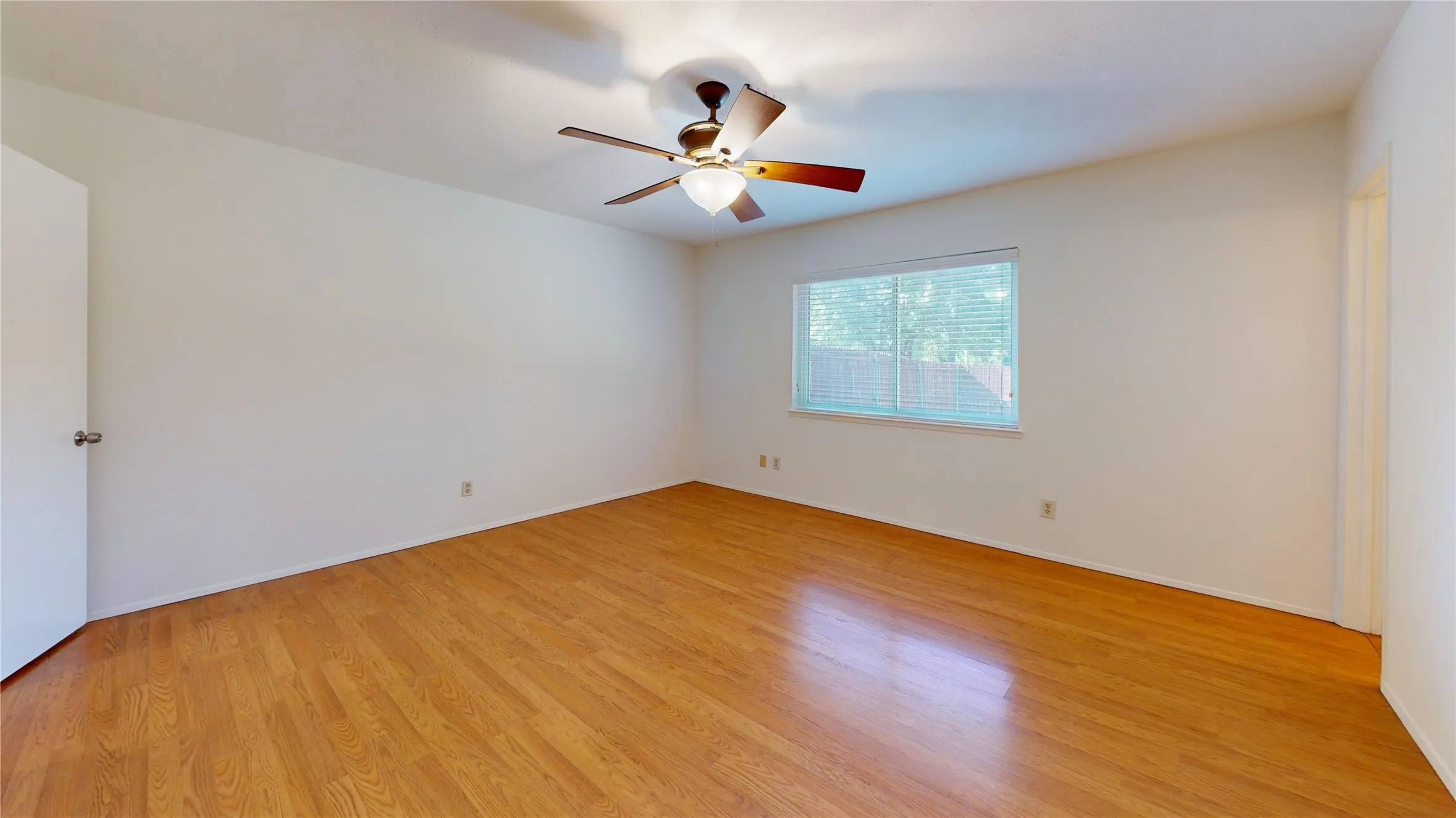 Wood-finish flooring, ceiling fan with integrated lighting, and a window with blinds