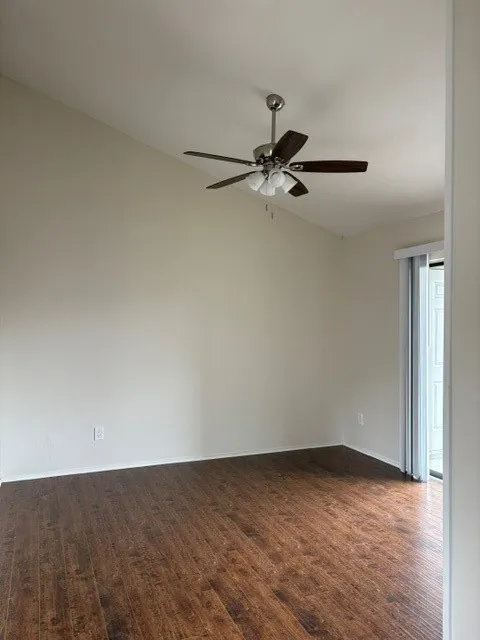 Vaulted ceiling with a ceiling fan light fixture, wood-finish flooring, and a sliding glass door