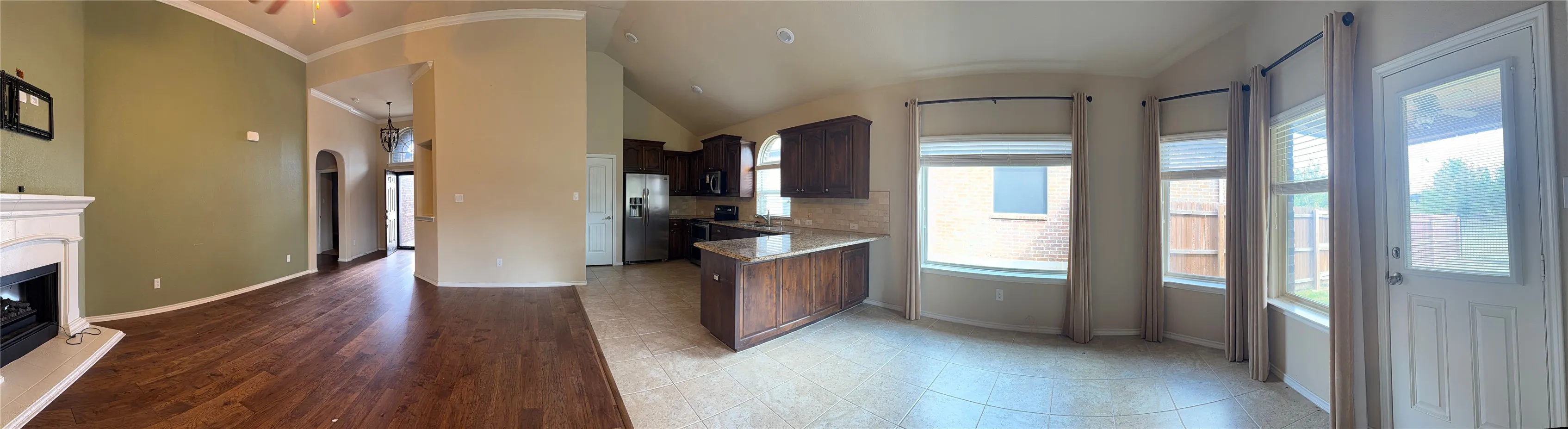 A panorama view of Family Room/Dining Room/Kitchen to see the open concept of interior of this lovely home. The breakfast bar separates the kitchen from the dining room.