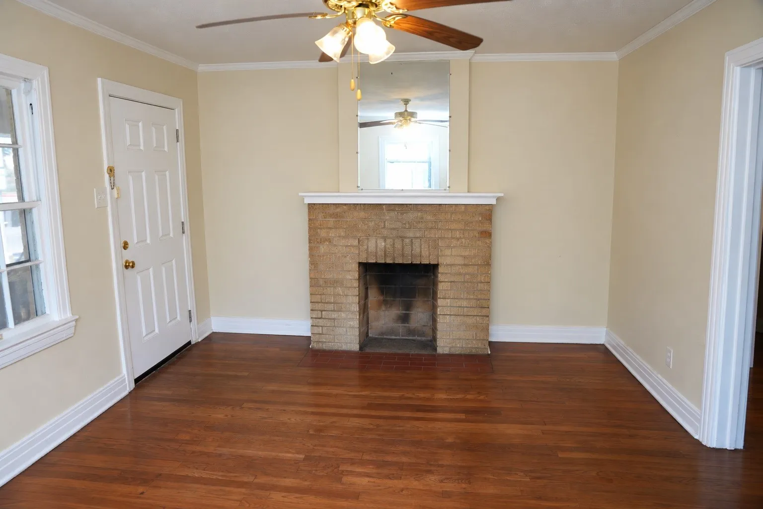Hardwood floors, original fireplace, and abundant natural light in vacant front unit.