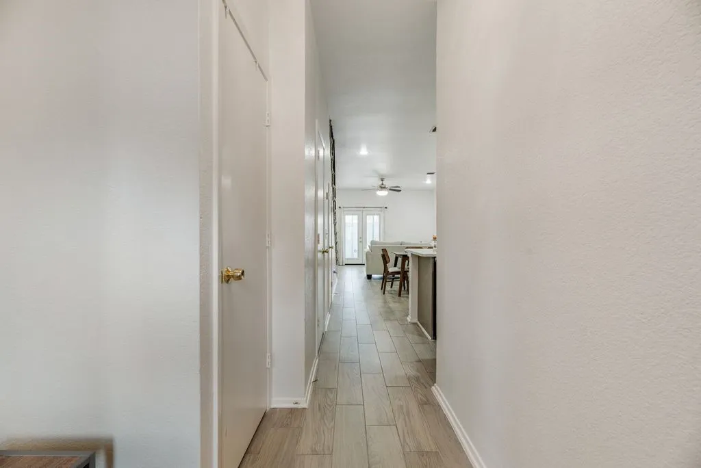 Hallway featuring wood-finish flooring, white doors with brass hardware, and recessed lighting