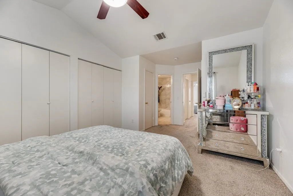 Vaulted ceiling, ceiling fan, neutral carpet flooring, white walls, and built-in closet storage