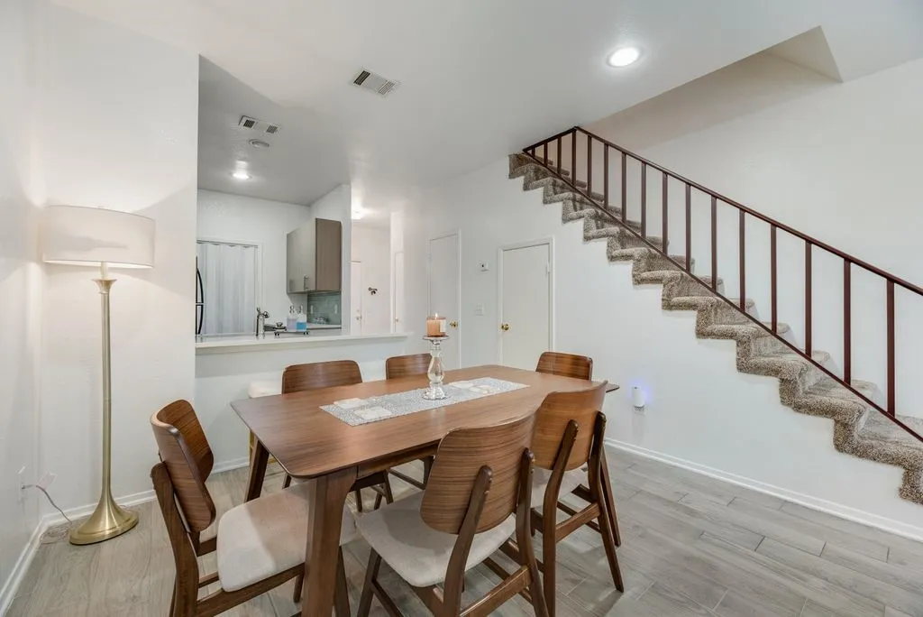 Wood-finish flooring throughout, with a carpeted staircase featuring a metal railing