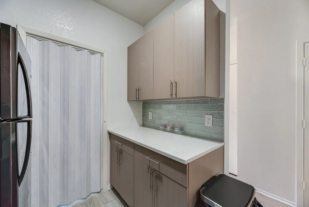 Built-in cabinetry with ample storage, light-colored countertops, and a modern subway tile backsplash