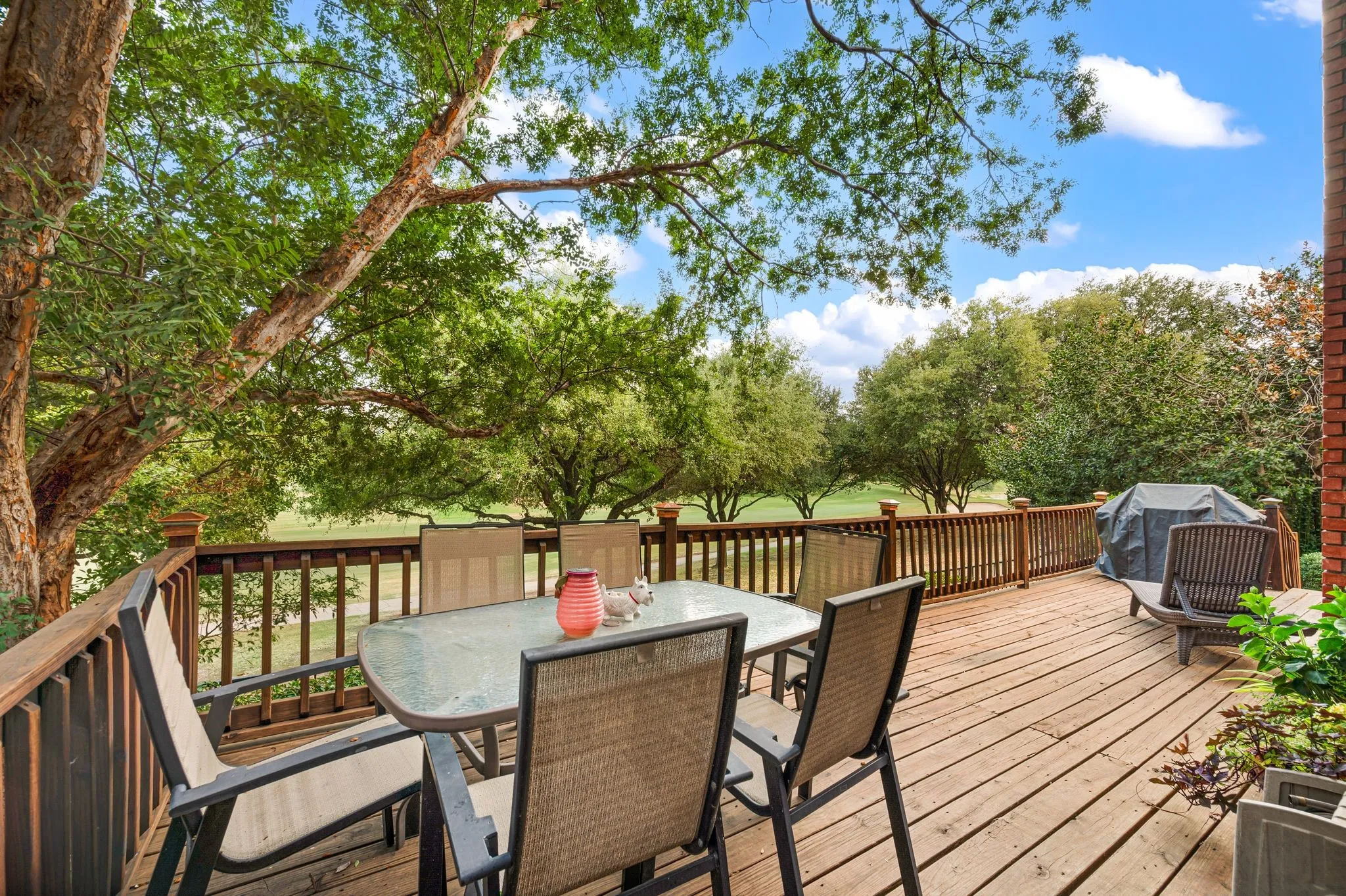 Expansive wood deck with a full-height wood railing, surrounded by mature trees