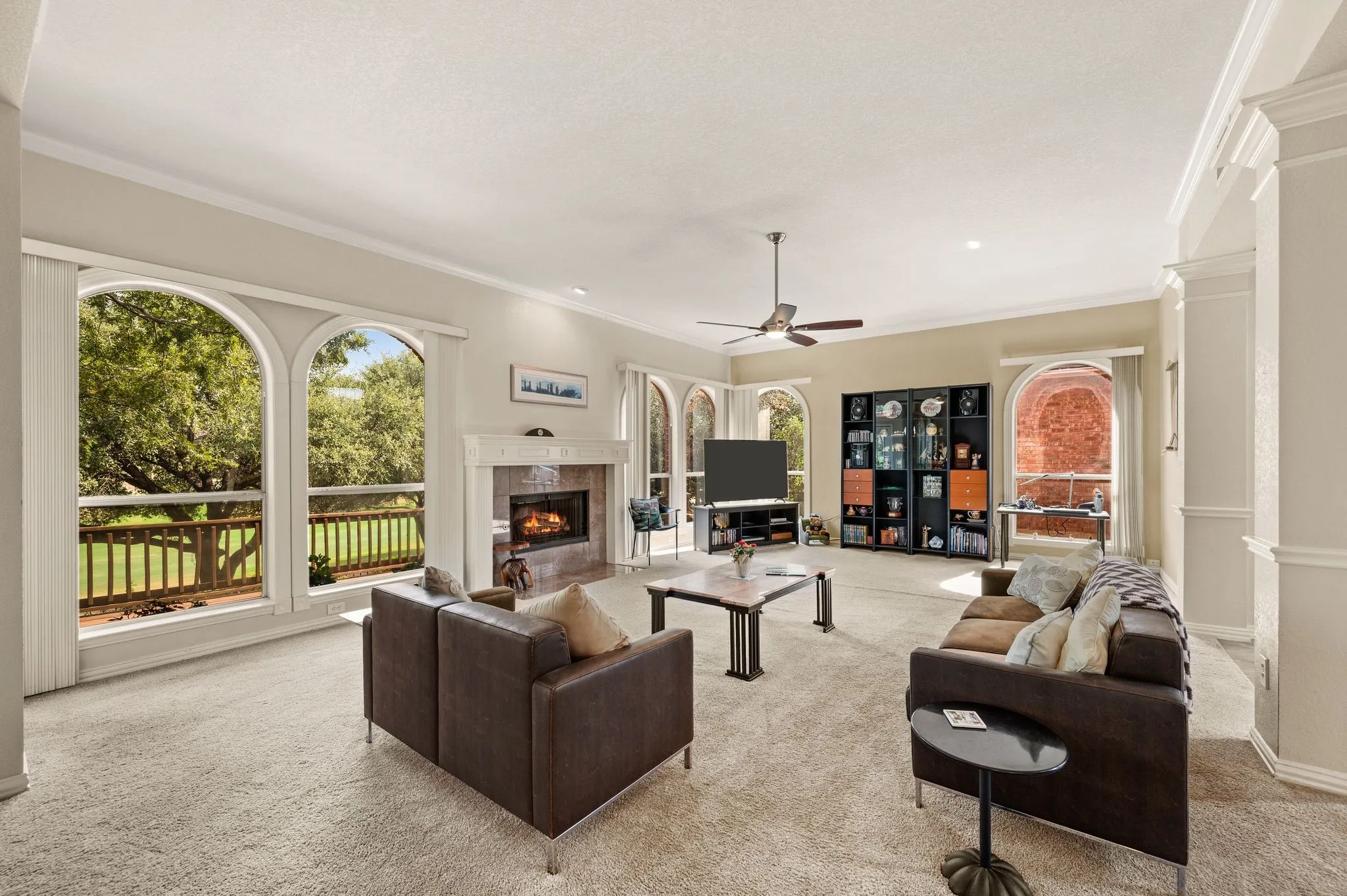 Living area featuring a fireplace with a mantel, multiple arched windows, recessed lighting, and a ceiling fan